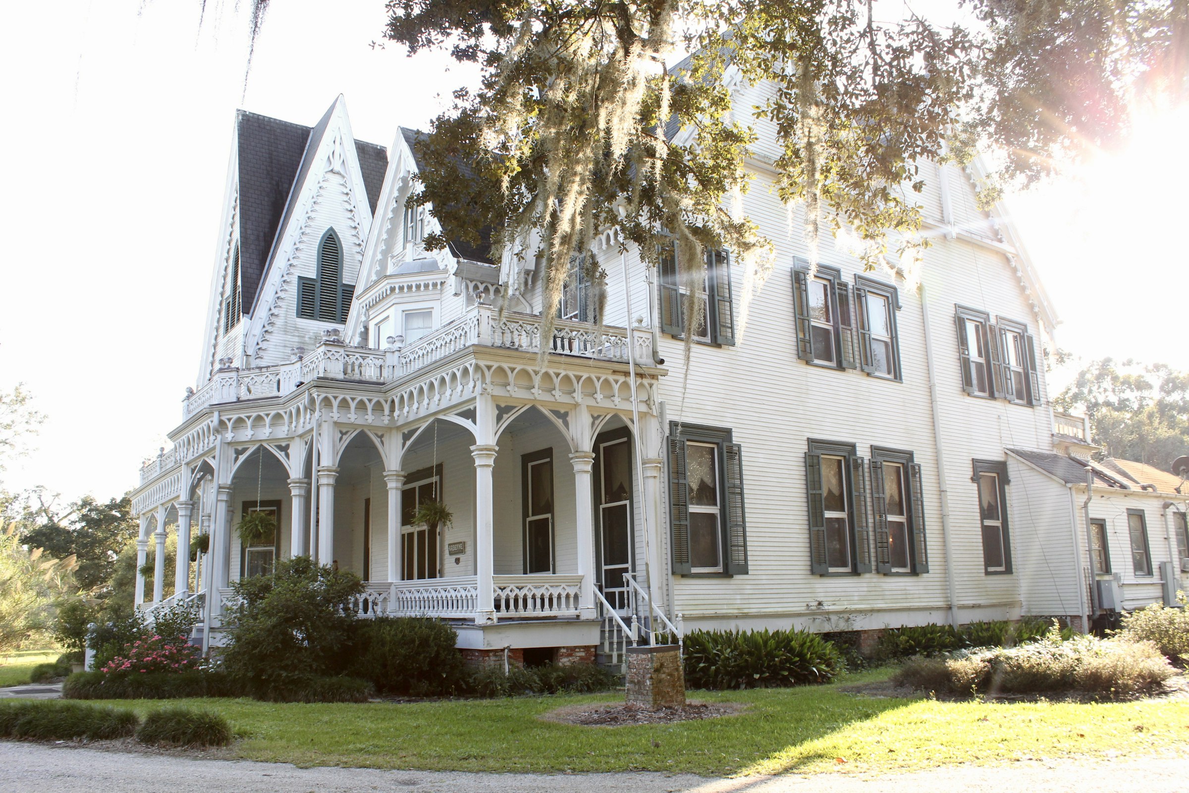 Beautiful ornate white Victorian home with gingerbread trim and a wraparound porch